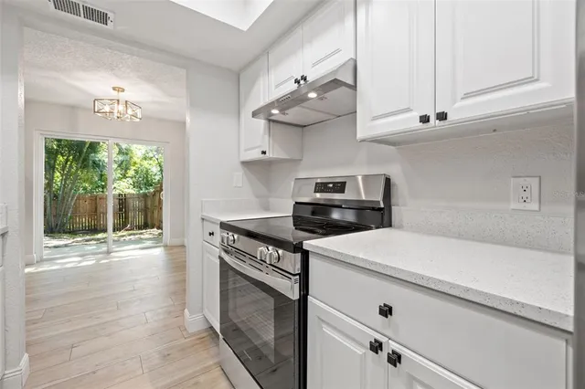 a kitchen with stainless steel appliances white cabinets and wooden floors