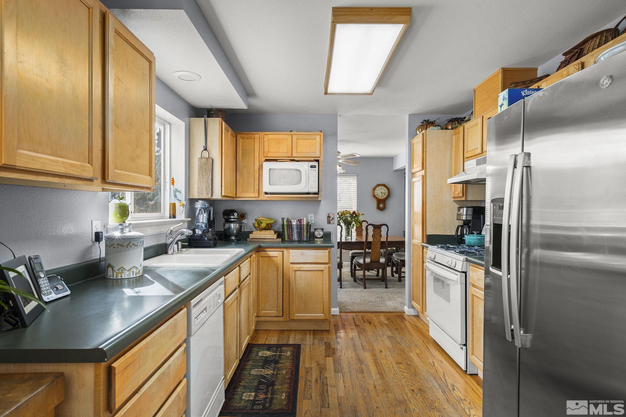 3160 Knight Road Reno, NV 89509 - Photo 9 of 39 a kitchen with stainless steel appliances granite countertop a refrigerator a sink dishwasher a stove and white countertops with wooden floor