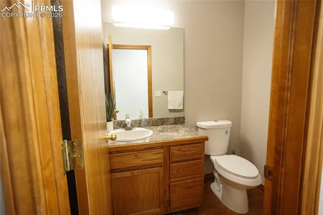 a bathroom with a granite countertop toilet a sink and a mirror