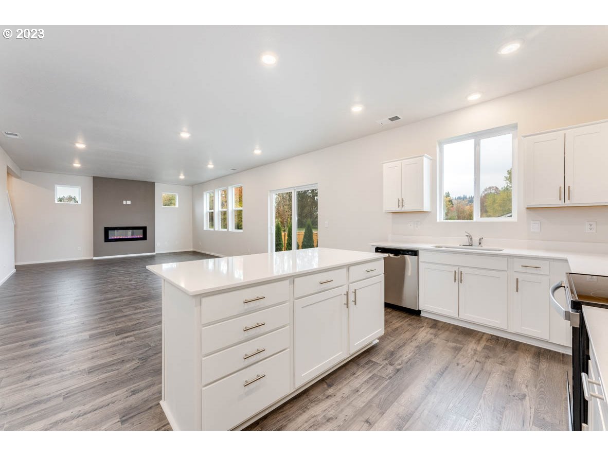 5629 Earth Street Northeast Dallas, OR 97338 - Photo 11 of 35 a kitchen with stainless steel appliances kitchen island granite countertop a stove a sink a refrigerator and white cabinets with wooden floor