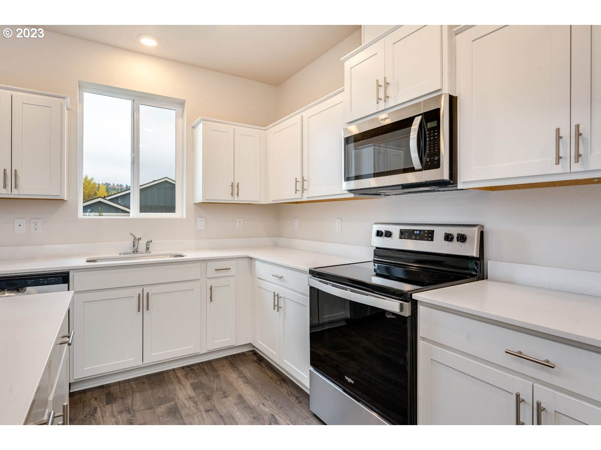 5629 Earth Street Northeast Dallas, OR 97338 - Photo 10 of 35 a kitchen with stainless steel appliances granite countertop white cabinets a stove a microwave and a sink