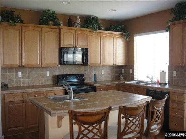 10593 Blockade Drive Reno, NV 89521 - Photo 2 of 9 a kitchen with stainless steel appliances granite countertop a sink a microwave cabinets and a dining table