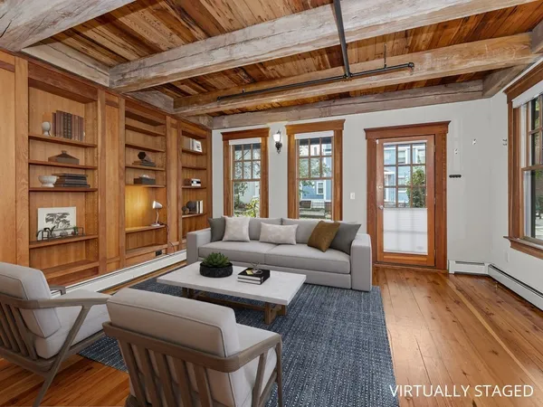 a living room with furniture a wooden floor and next to a window