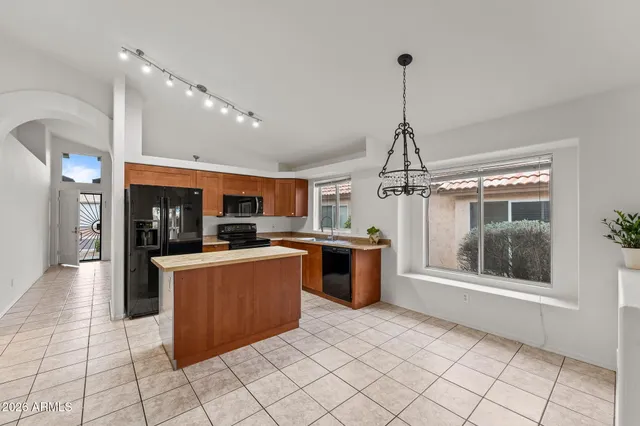 a kitchen with stainless steel appliances kitchen island granite countertop a refrigerator stove top oven and sink