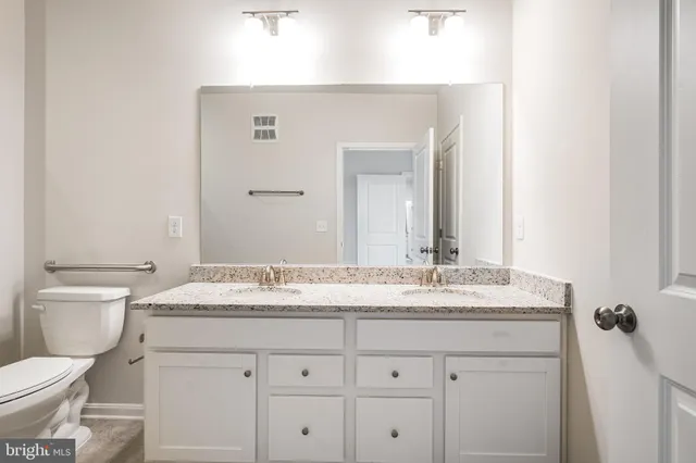 a bathroom with a granite countertop sink vanity mirror and toilet