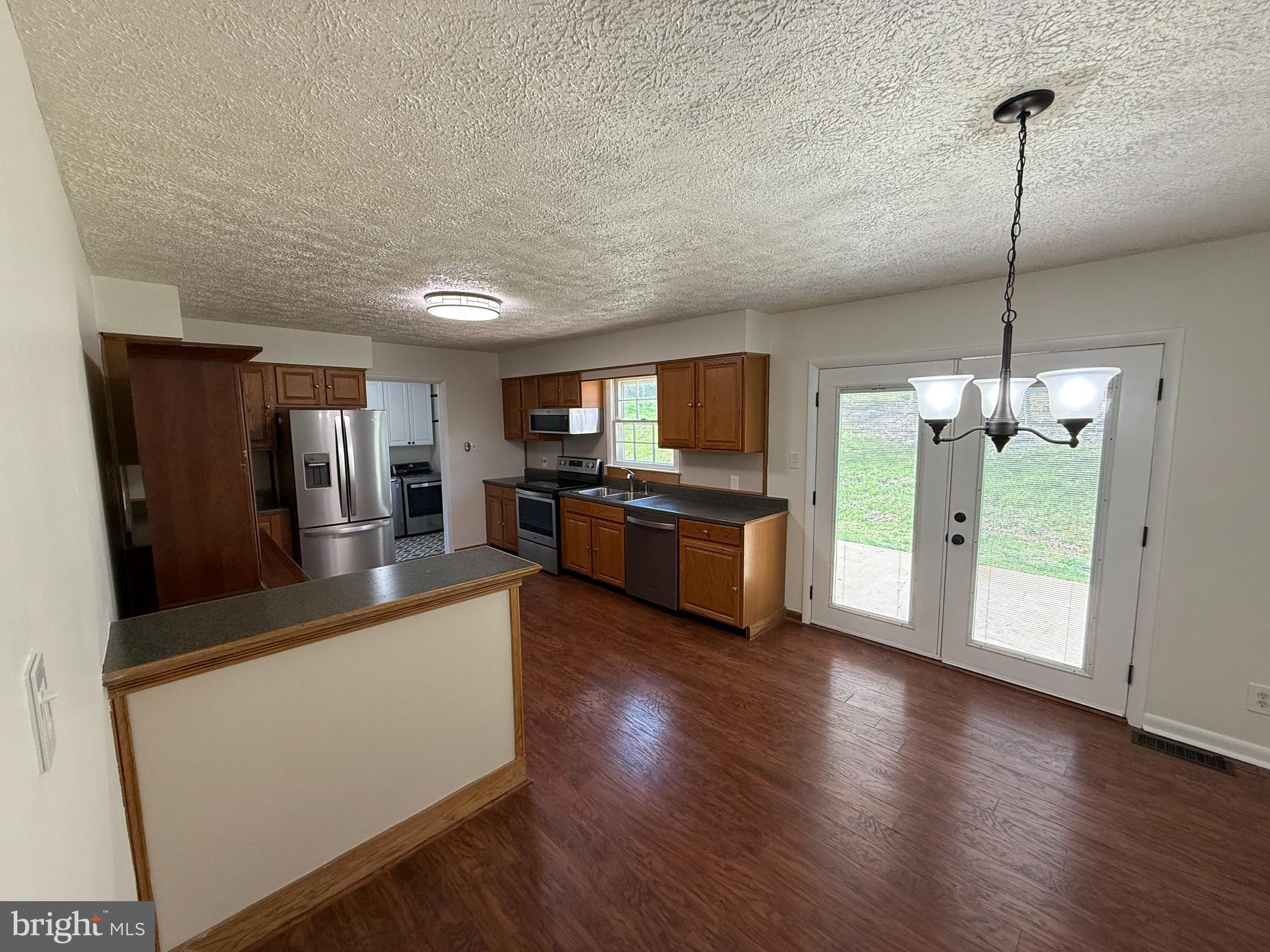 5572 Old Bust Head Road Broad Run, VA 20137 - Photo 12 of 30 a large kitchen with stainless steel appliances granite countertop a refrigerator a oven a stove and a wooden floor