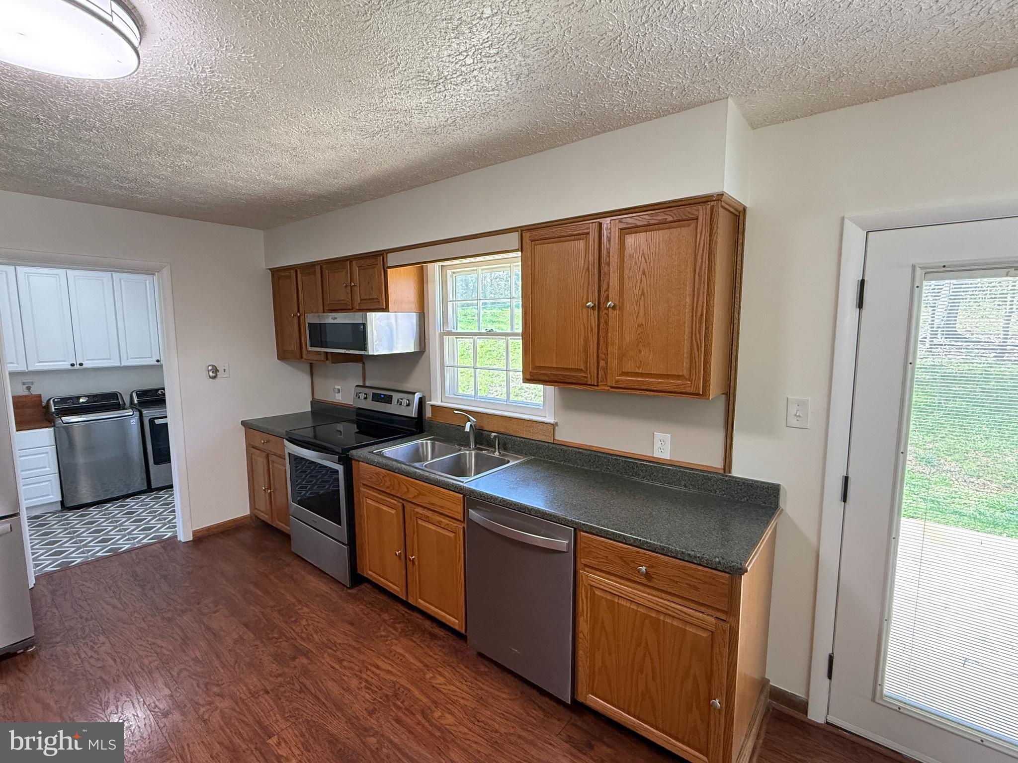 5572 Old Bust Head Road Broad Run, VA 20137 - Photo 14 of 30 a kitchen with stainless steel appliances granite countertop wooden cabinets a refrigerator a sink a stove a microwave and wooden floors
