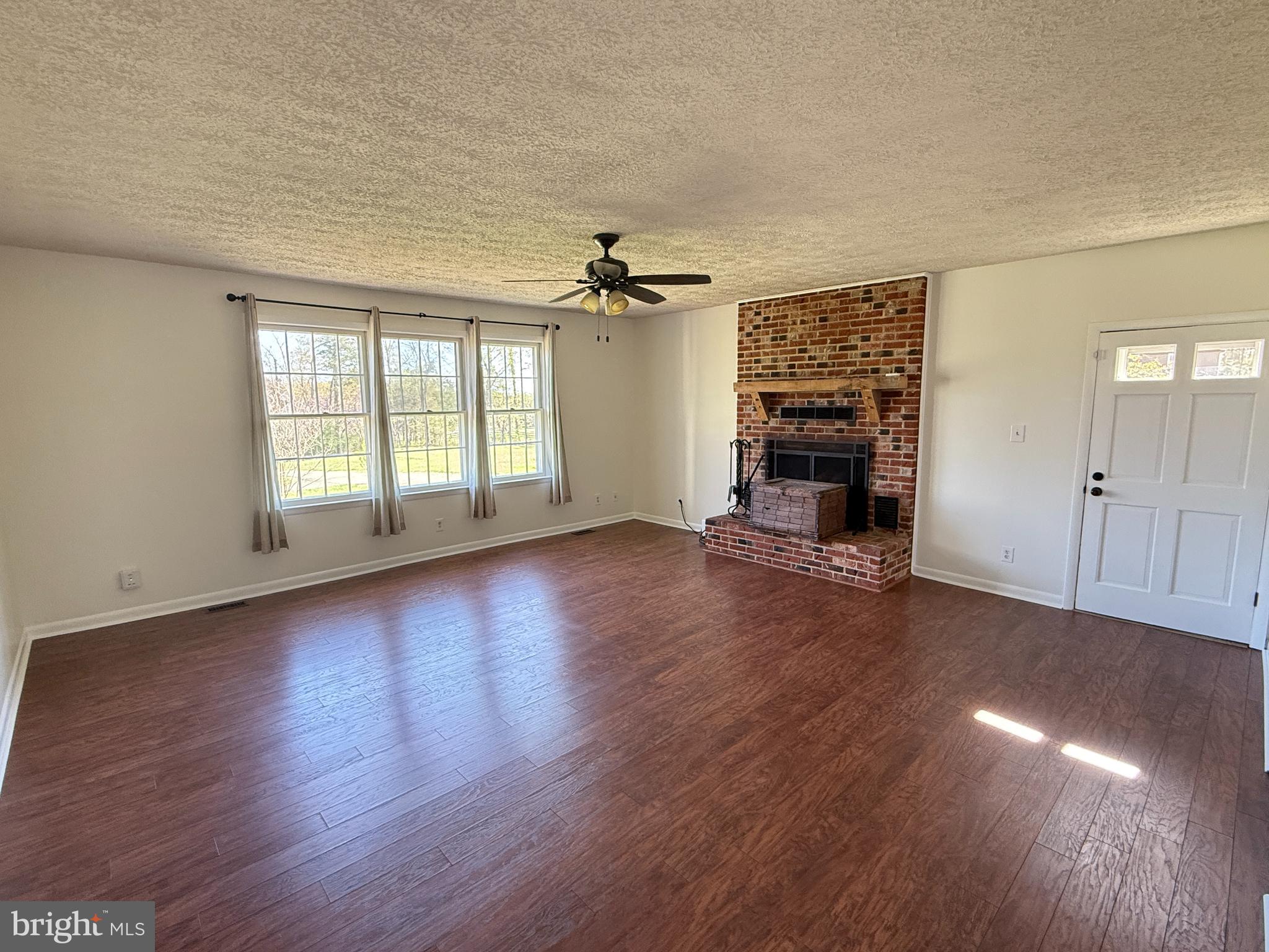 5572 Old Bust Head Road Broad Run, VA 20137 - Photo 17 of 30 an empty room with wooden floor fireplace and windows