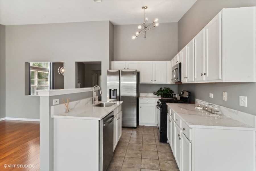 115 Periwinkle Lane Bolingbrook, IL 60490 - Photo 5 of 15 a kitchen with a sink a stove top oven a refrigerator and white cabinets