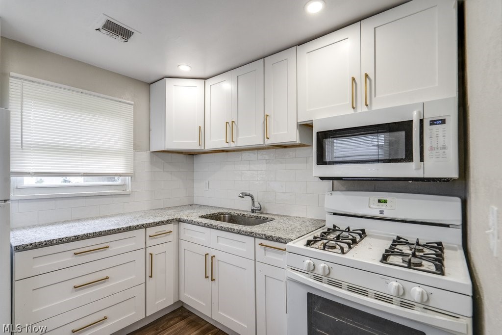 396 Niagara Road Vermilion, OH 44089 - Photo 7 of 15 Contemporary kitchen featuring white cabinetry, granite-patterned countertops, a stainless steel sink, and wood-finish flooring