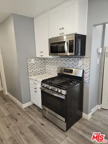 a kitchen with stainless steel appliances and wooden floor