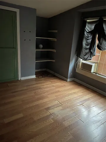 a view of an empty room with wooden floor and closet