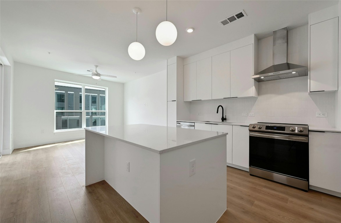 a kitchen with stainless steel appliances granite countertop a sink a stove and a wooden floors