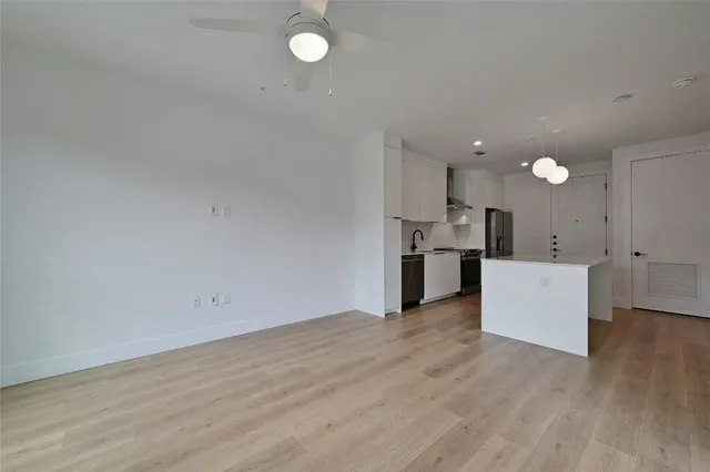 an empty room with wooden floor and a kitchen