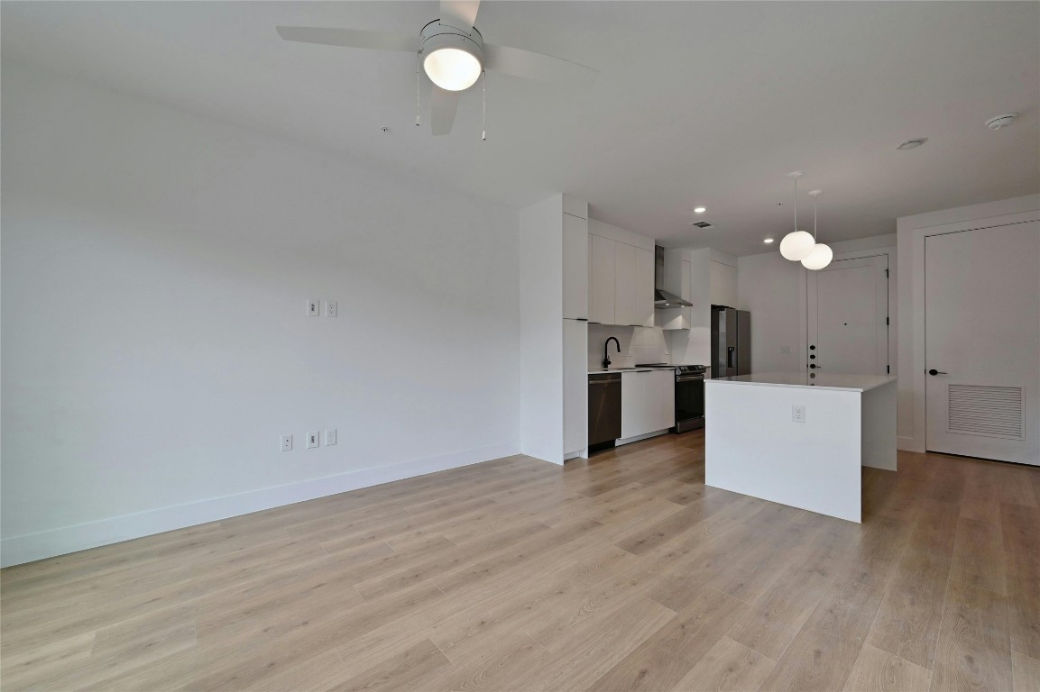 1701 Simond Avenue, Unit 328 Austin, TX 78723 - Photo 11 of 35 an empty room with wooden floor and a kitchen