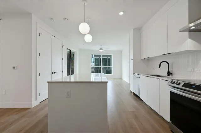 a large white kitchen with sink stove and cabinets