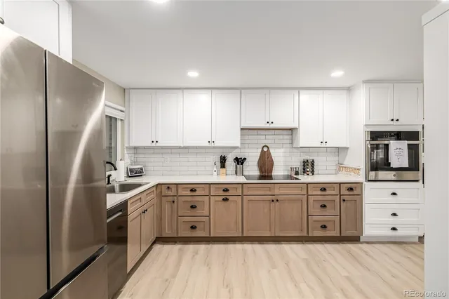 a kitchen with stainless steel appliances granite countertop white cabinets a sink dishwasher a refrigerator and white cabinets with wooden floor