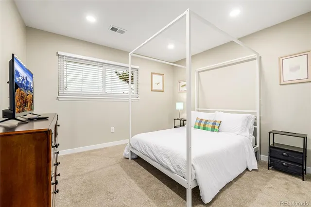 a bedroom with a bed and a flat tv screen on the dresser