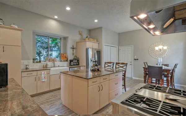 a kitchen with granite countertop kitchen island stainless steel appliances a sink stove and refrigerator