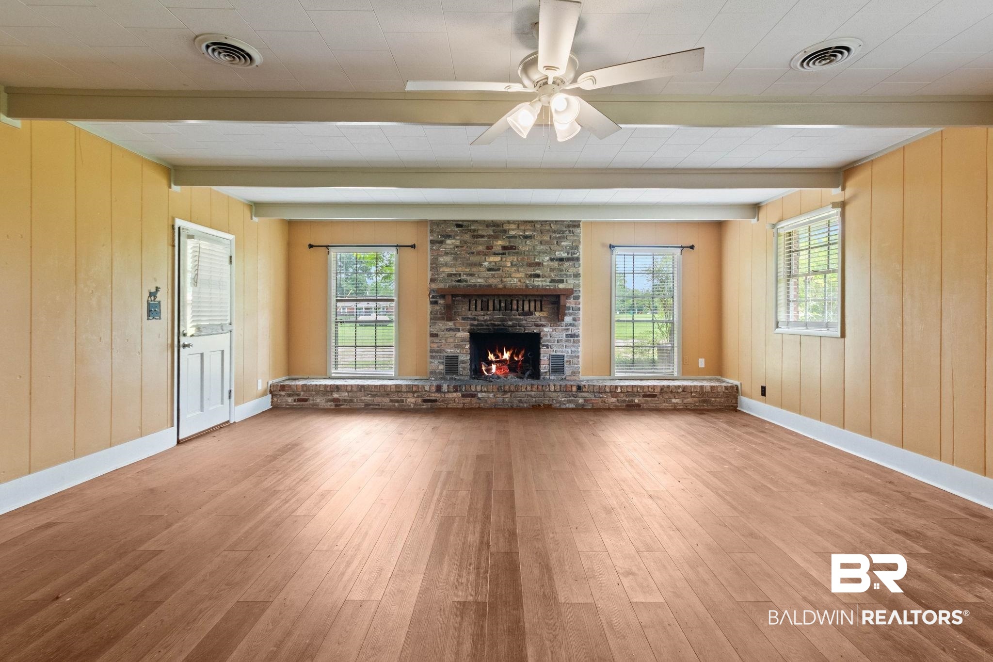 384 Old Bratt Road Atmore, AL 36502 - Photo 13 of 64 Spacious room featuring wood-finish flooring, a brick fireplace with a raised hearth, and exposed ceiling beams