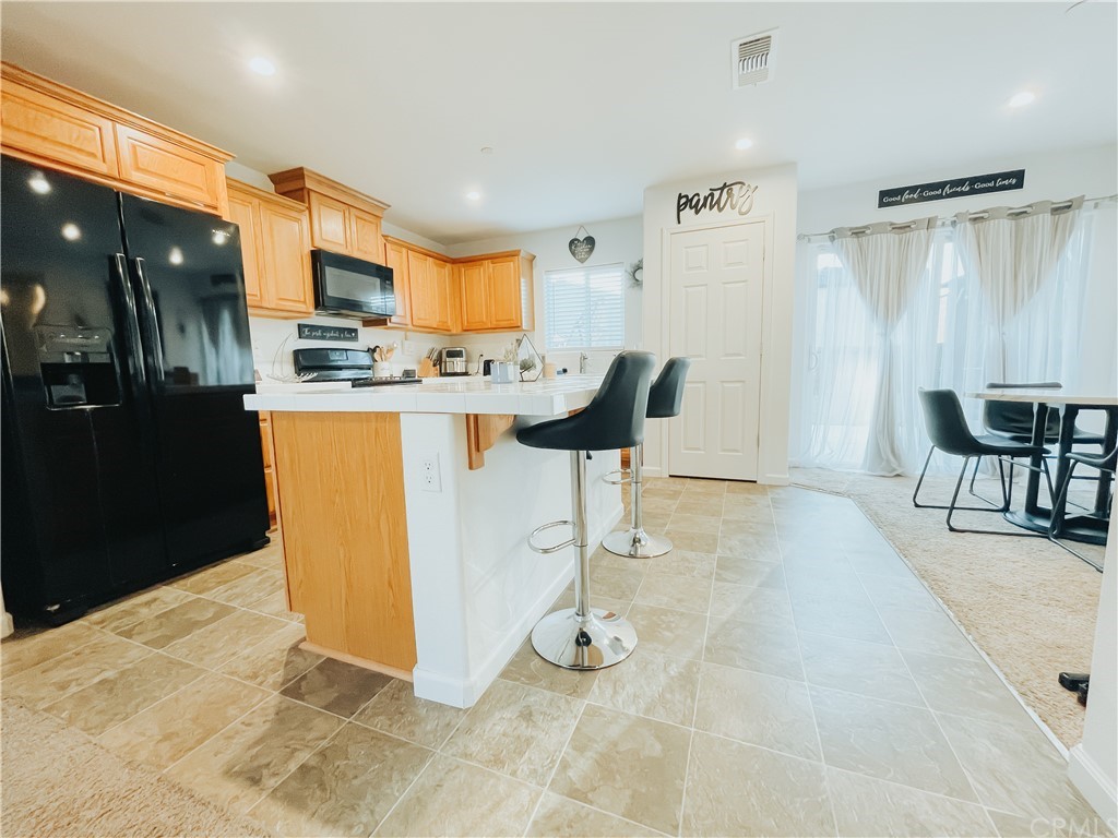 385 Ostrander Avenue Merced, CA 95341 - Photo 4 of 12 a view of a kitchen with kitchen island dining table and stainless steel appliances