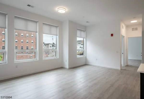 a view of an empty room with a window and wooden floor