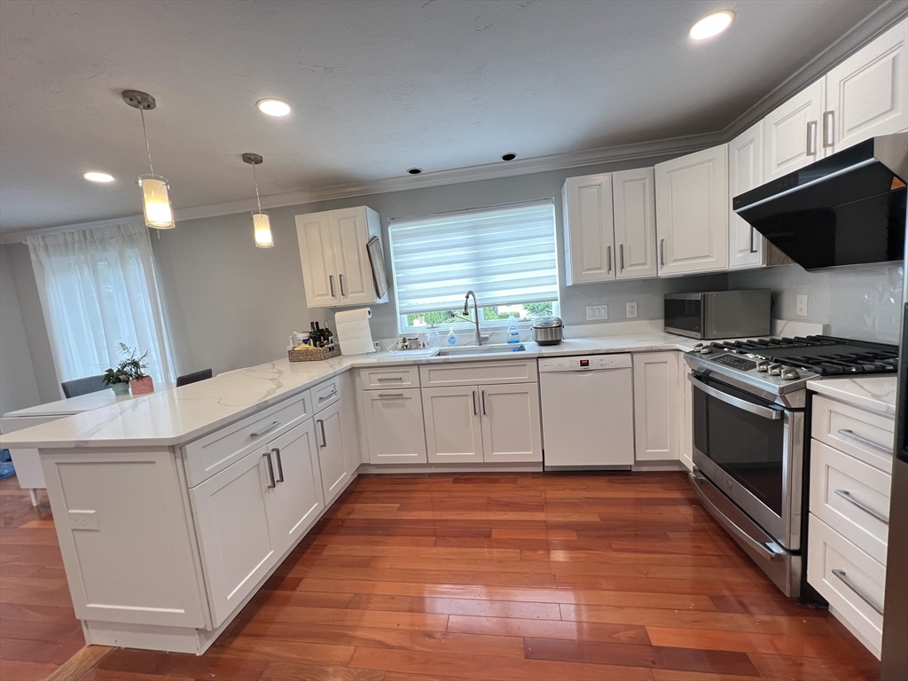 46 Suomi Road, Unit 46 Quincy, MA 02169 - Photo 2 of 16 a kitchen with stainless steel appliances a white stove top oven a sink dishwasher and a refrigerator with wooden floor