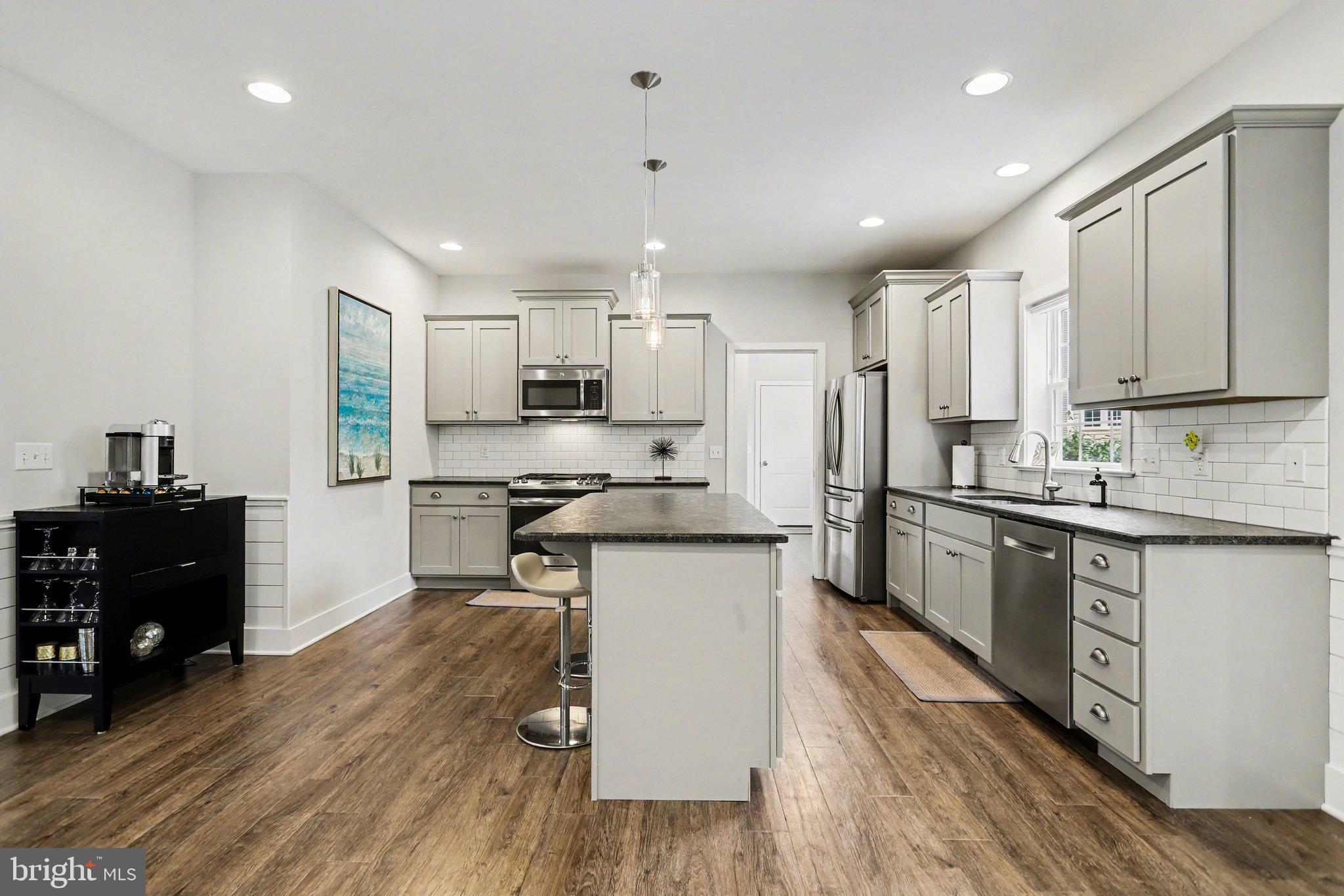 401 Wendover Way Lancaster, PA 17603 - Photo 12 of 45 a kitchen with kitchen island granite countertop wooden floors white cabinets and stainless steel appliances