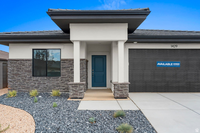 1624 South Staircase Way, Unit 4183 Washington, UT 84780 - Photo 3 of 47 Modern exterior featuring a stone and stucco facade, a prominent teal entry door, a textured garage door, and a low-maintenance landscape design with decorative rock