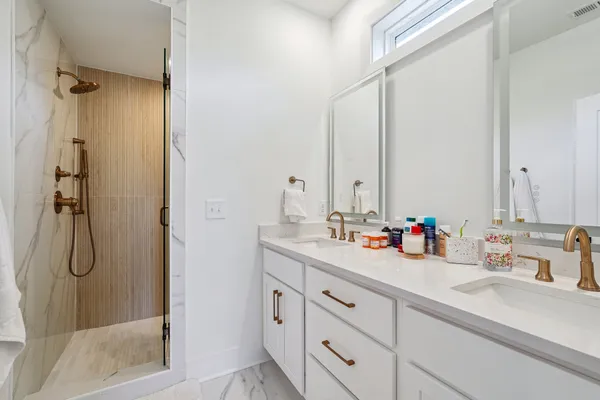 a bathroom with a double vanity sink mirror and shower
