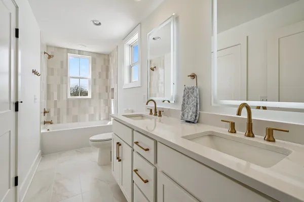 a bathroom with a double vanity sink toilet mirror and bathtub