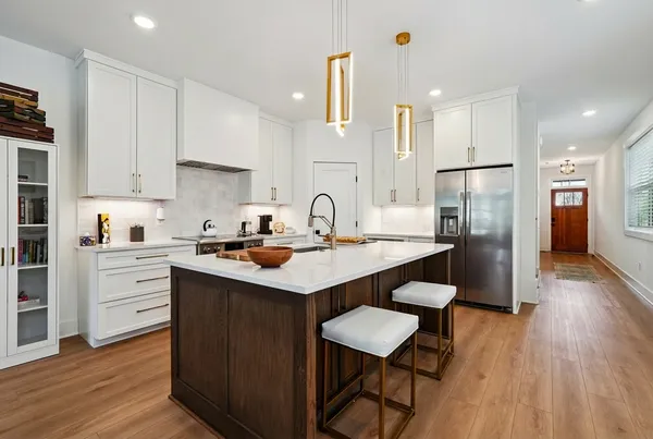 a kitchen with stainless steel appliances granite countertop a sink a stove a refrigerator and island with wooden floor