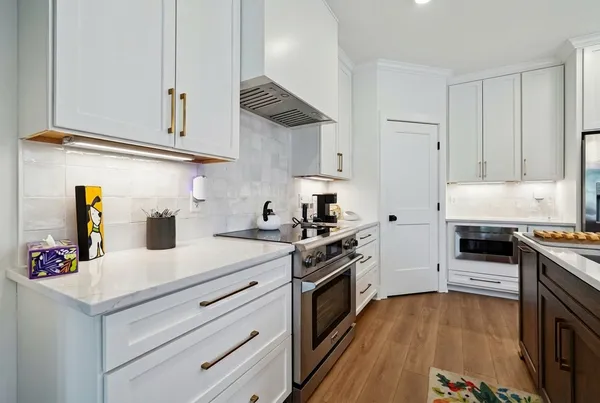 a kitchen with stainless steel appliances white cabinets and a stove top oven