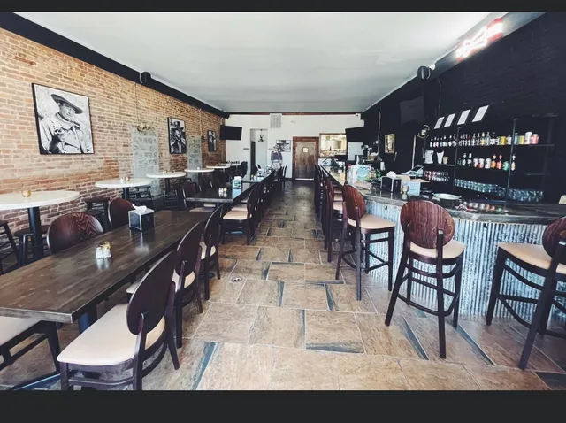 a living room with lots of furniture a rug kitchen view and a large window