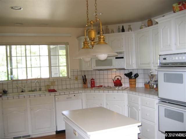 4390 Bitteroot Road Reno, NV 89519 - Photo 4 of 9 a kitchen with stainless steel appliances granite countertop a sink dishwasher and white cabinets with wooden floor