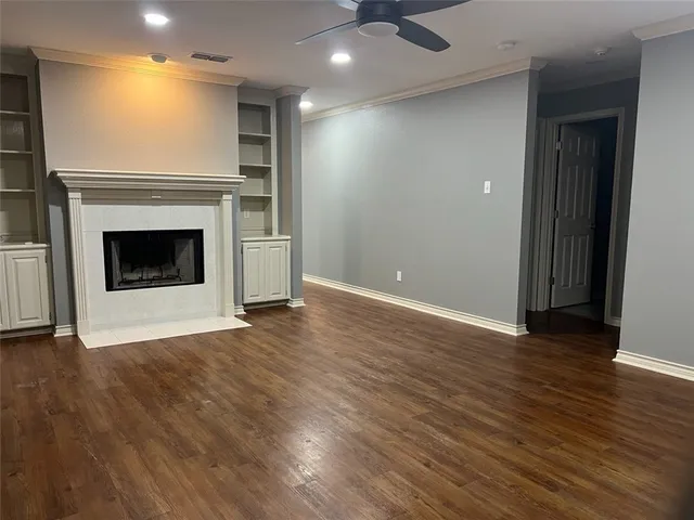 an empty room with wooden floor a fireplace and windows