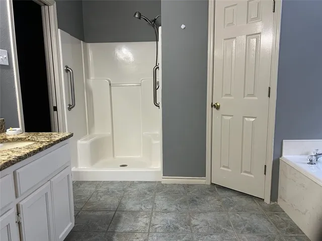 a bathroom with a granite countertop sink a mirror and a bathtub