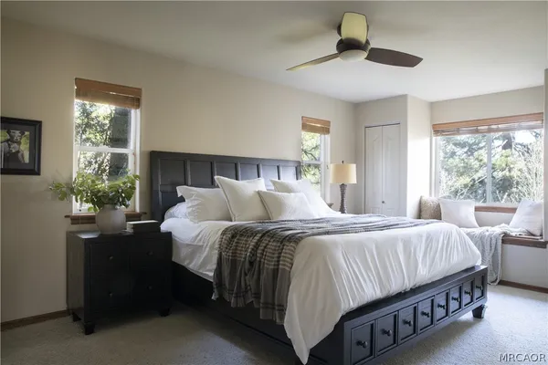 a bedroom with a large bed and a chandelier fan