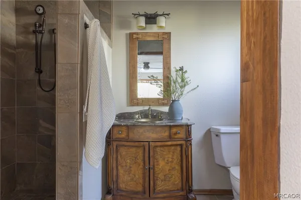 a bathroom with a granite countertop sink a toilet and shower