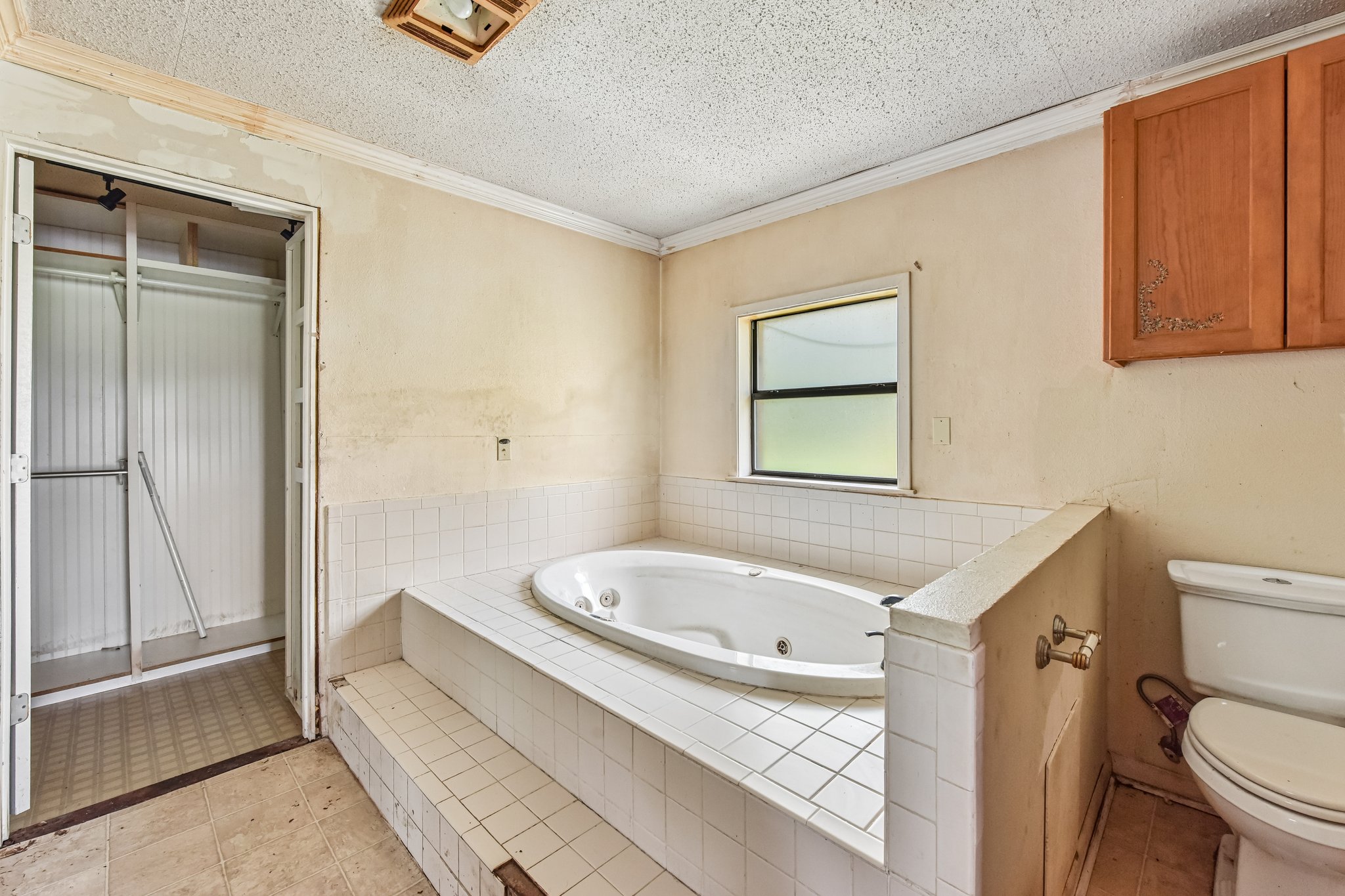 1111 Silent Valley Road Lockhart, TX 78644 - Photo 12 of 14 A spacious bathroom awaiting transformation, featuring a built-in soaking tub and a walk-in closet.