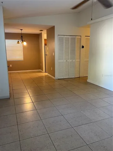 a view of an empty room with window and chandelier fan