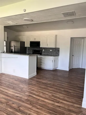 a kitchen with stainless steel appliances wooden floor and a sink