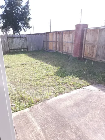 a view of a backyard with a large tree and wooden fence