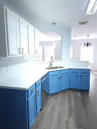 a kitchen with stainless steel appliances a sink cabinets and wooden floor
