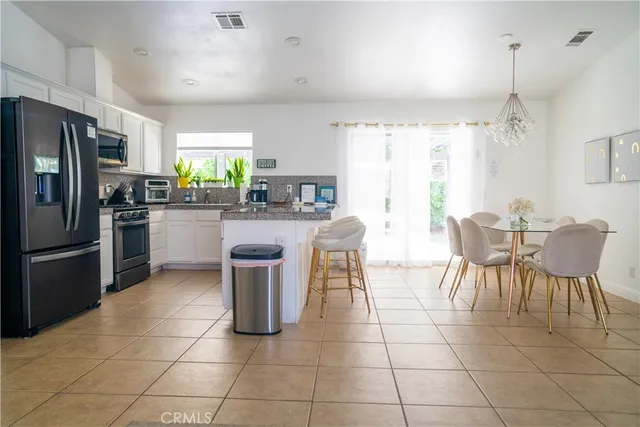 a kitchen with stainless steel appliances a dining table chairs stove refrigerator and cabinets