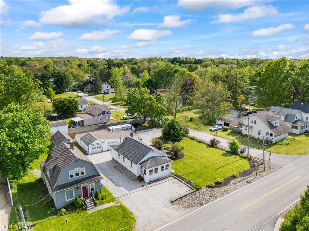 258 Randolph Road Mogadore, OH 44260 - Photo 2 of 49 Aerial perspective showcasing multiple properties, including a light blue home with a red entry door and dormer windows, a white structure with a dark roof and an attached garage, and a third white residence with a deck