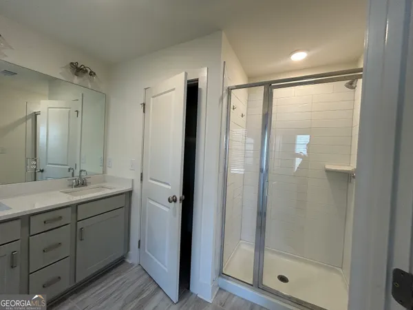 a bathroom with a granite countertop sink a mirror and a shower