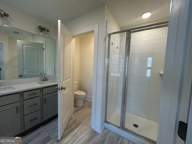 a bathroom with a granite countertop sink a toilet and shower