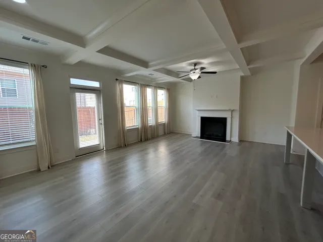 a view of living room with kitchen island stainless steel appliances wooden floor and flat screen tv