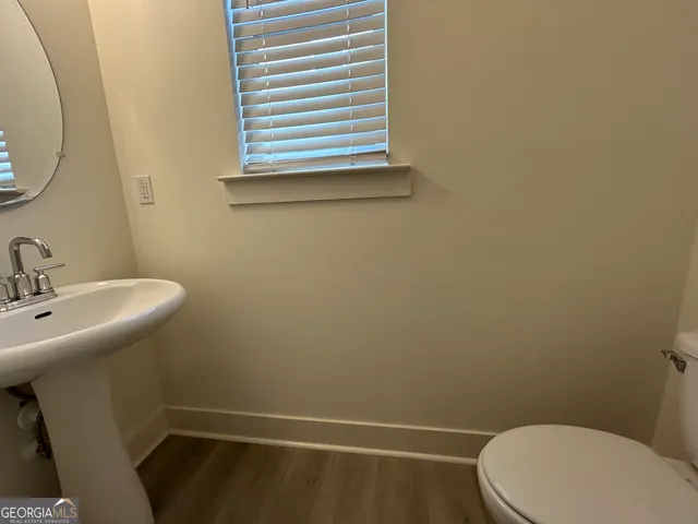a view of an empty room with wooden floor and windows